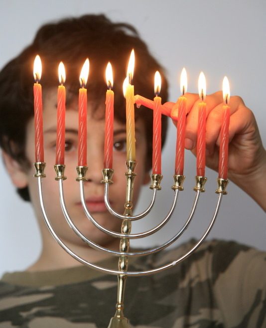 Boy lighting Hanukkah candles